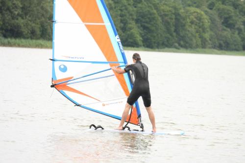 a man standing on a surfboard with a sail at Sodyba Brazylija in Taraldžiai