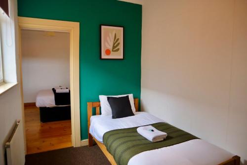 Un pequeño dormitorio con una pared verde y una cama en Equipped 5bed 2bath House in Coventry City FREE PARKING AMENITIES ROADLINKS WI-FI SMART TV en Coventry
