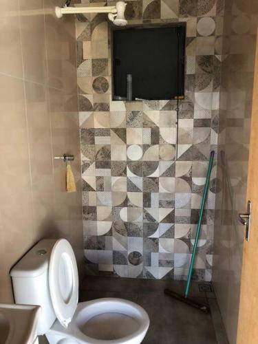 a bathroom with a toilet and a tv on the wall at Recanto do sol in Extrema