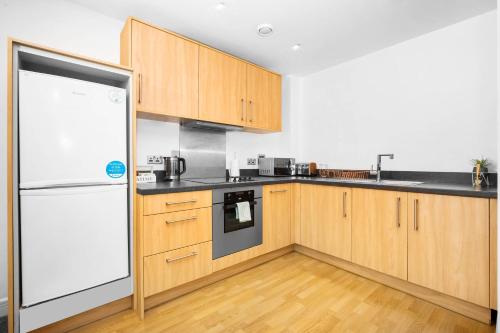 a kitchen with wooden cabinets and a white refrigerator at Birmingham City Centre Deluxe Apartment - Top Rated - 36C in Birmingham