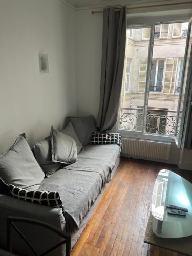 - un canapé dans une chambre avec une grande fenêtre dans l'établissement Paris - Champs Élysées - Arc de Triomphe, à Paris