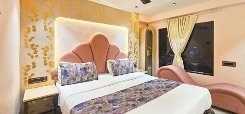 a hotel room with a bed and a chair and a window at Hotel Nova Bling in Rajkot