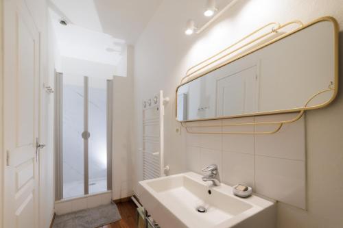 une salle de bain blanche avec un lavabo et un miroir dans l'établissement Domaine de l'Orangerie - La Roseraie, à Boissise-la-Bertrand