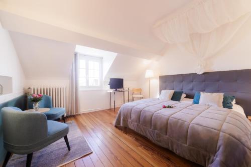 une chambre avec un grand lit et une chaise dans l'établissement Domaine de l'Orangerie - La Roseraie, à Boissise-la-Bertrand