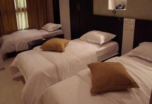 three beds in a room with white sheets and pillows at DAR EL IKRAM HOTEL in Alger