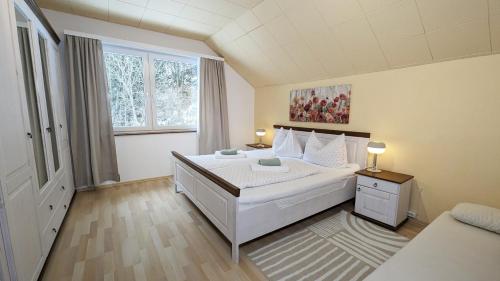 Un dormitorio con una gran cama blanca y una ventana en Ferienwohnung Edeltraud, fußläufig zum See und 20 Minuten vom Skigebiet entfernt, en Döbriach