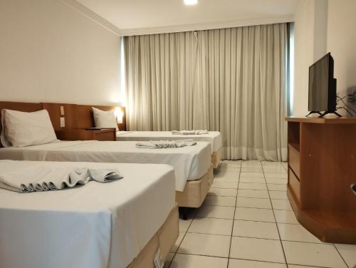 a hotel room with two beds and a flat screen tv at PONTA NEGRA FLAT APART in Natal