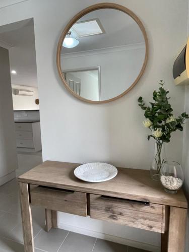a mirror on a wall above a wooden table with a sink at Yass Valley Stays - Convenient & Comfortable in Yass