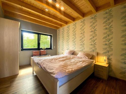 1 dormitorio con cama y ventana en Ferienwohnung am Weiher - Wohnung 8 - Für 4 Personen en Nideggen