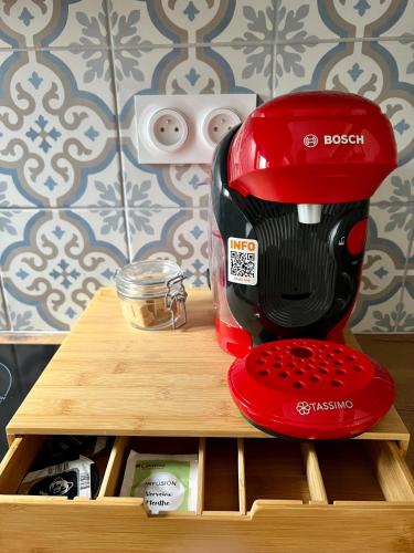 un mélangeur rouge assis au-dessus d'une étagère en bois dans l'établissement sainte Cécile 3: studio élégant idéalement situé, à Vichy