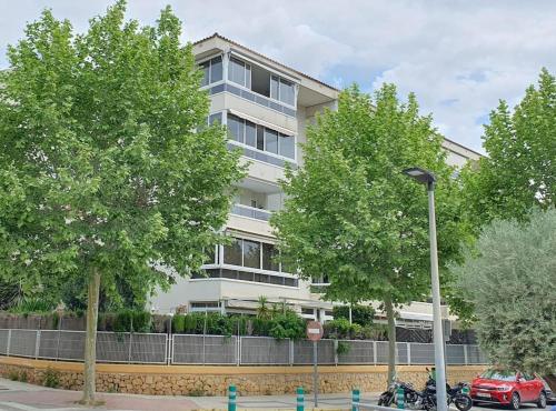 a tall white building with trees in front of it at Lys og trivelig leilighet sentralt i Albir in Albir