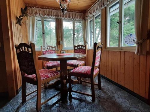 een eetkamer met een tafel, stoelen en ramen bij Waldhütte Allzunah in Ilmenau