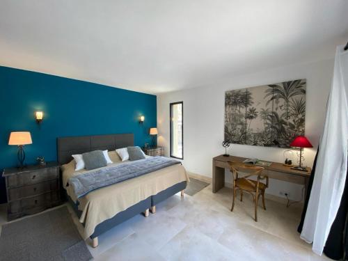 a bedroom with a blue wall and a bed and a desk at Villa Betty -piscine chauffée- in Paradou