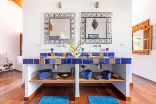 baño con lavabo de azulejos azules y espejos en La villa du Moulin Castin en Castin