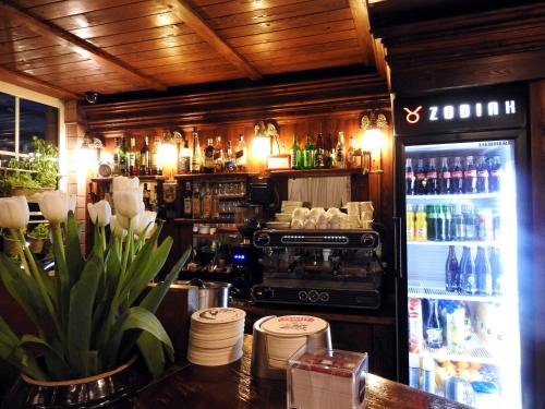 a bar with a refrigerator and a table with flowers at Noclegi I Restauracja Zodiak in Gliwice