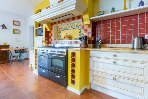 a kitchen with a stove and yellow and red tiles at La villa du Moulin Castin in Castin