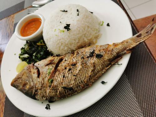 a plate of food with a fish and rice at New Safari Hotel in Chanjani