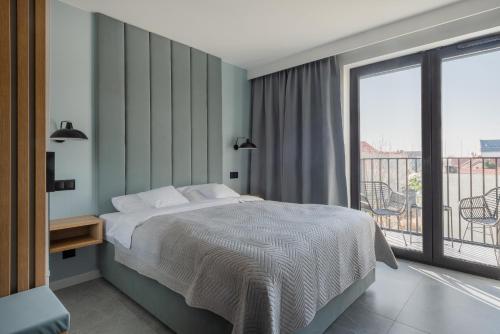 a bedroom with a bed and a balcony at AVAPARTS Apartament AQUA in Jastarnia