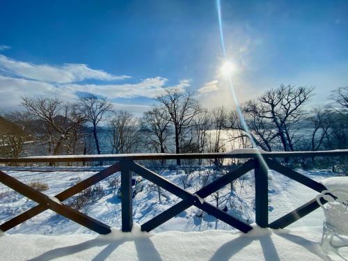 a fence covered in snow with the sun in the background at The Lobs, Lake Toya "former Yellow House by Lake Toya" in Tōya