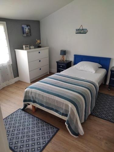 een slaapkamer met een bed met een gestreepte deken en een dressoir bij Gîte Domangé-Audenge in Audenge