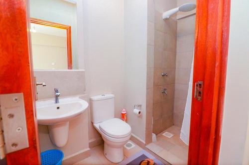 een badkamer met een toilet, een wastafel en een douche bij 1 Bedroom near TRM gate C in Nairobi