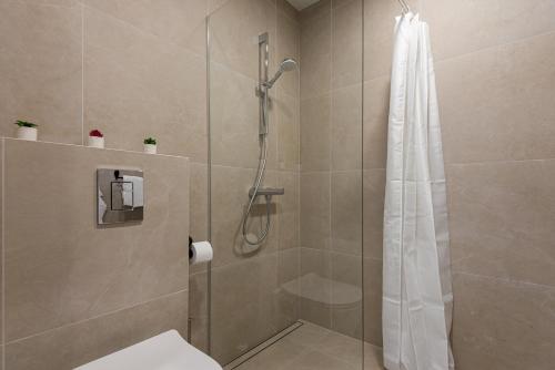 a bathroom with a shower with a shower curtain at KUTI apartamentai in Palanga