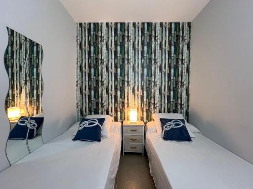 a room with two beds and a window with curtains at BLAU Apartamento frente a los canales y las puestas de sol de Roses in Roses