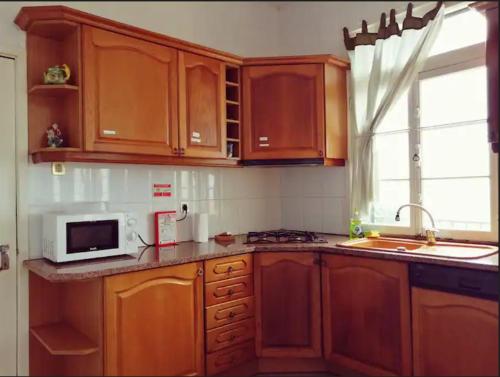 a kitchen with wooden cabinets and a microwave at Vila São Gonçalo in Funchal