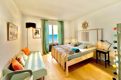 a bedroom with a bed and a chair and a window at Glaz Ocean in Douarnenez