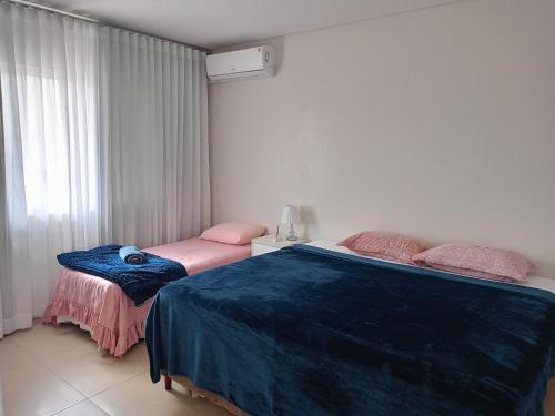 1 dormitorio con 2 camas y ventana en Pousada Donatella, en Paranaguá
