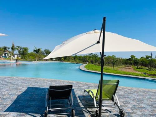 Magomba的住宿－Tree Tops Game Resort，游泳池前的两把椅子和一把遮阳伞