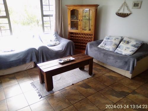 a living room with two beds and a coffee table at Streams Cottage in Bettyʼs Bay