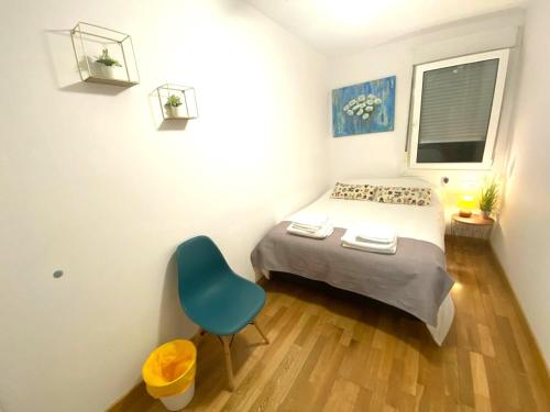 a small bedroom with a bed and a blue chair at Apartamentos Parke24 - San Sebastian in Rentería