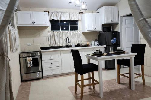 a kitchen with white cabinets and a table with chairs at Welcome to our 1 bedroom villa in Bridgetown