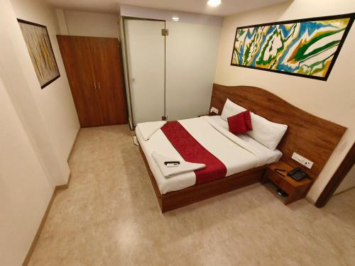 a bedroom with a bed with a wooden head board at Hotel Beach Crown Juhu in Mumbai