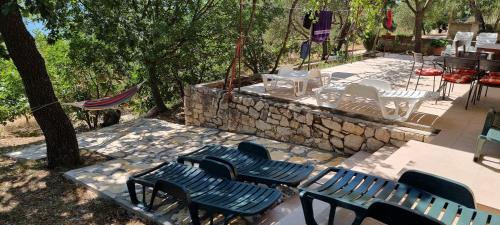 a group of benches and tables and a stone wall at Beachfront House Nella with full privacy in Jasenice