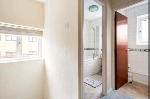 ロンドンにあるLondon Stratford Holiday Homeのバスルーム(バスタブ、トイレ付)、窓が備わります。