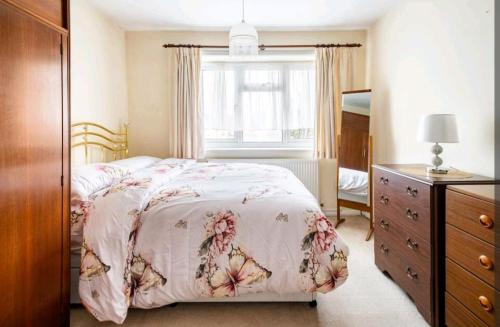 a bedroom with a bed and a dresser and a window at London Stratford Holiday Home in London