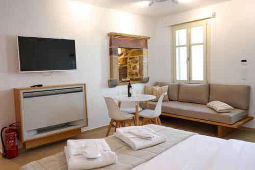 a living room with a couch and a tv and a table at Castrusso Castle apartments in Chios