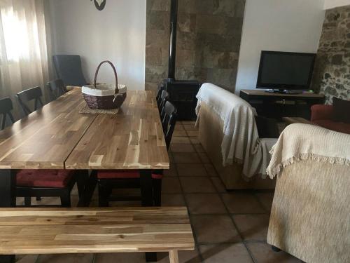 a dining room with a wooden table and a television at Casa Rural La Encina in Azuel