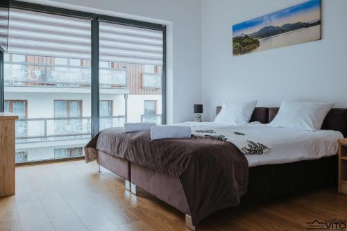 a bedroom with a large bed and a large window at Kompleks Tawerna Vito - Apartamenty Vito in Czorsztyn