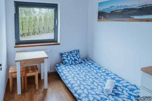 a bedroom with a bed and a desk and a window at Kompleks Tawerna Vito - Apartamenty Vito in Czorsztyn