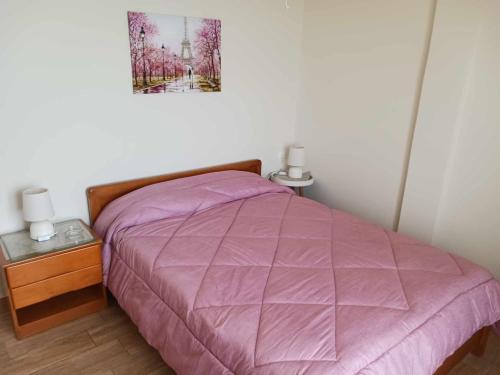 a bed with a purple comforter in a bedroom at FIORE ROOMS in Akrotiri