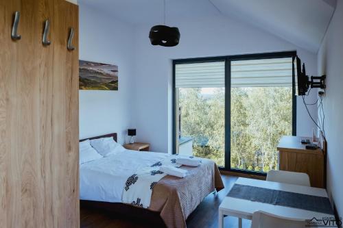 a bedroom with a bed and a large window at Kompleks Tawerna Vito - Apartamenty Vito in Czorsztyn