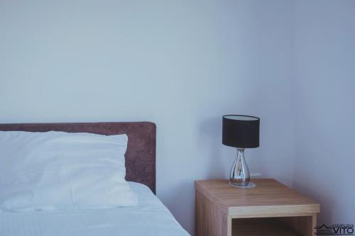 a bed with a nightstand with a lamp on it at Kompleks Tawerna Vito - Apartamenty Vito in Czorsztyn