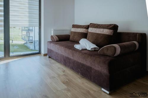 a brown couch with a pillow on it in a living room at Kompleks Tawerna Vito - Apartamenty Vito in Czorsztyn