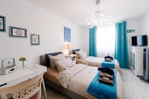 a bedroom with two beds with blue curtains and a desk at GästeHaus am Flughafen Düsseldorf in Düsseldorf