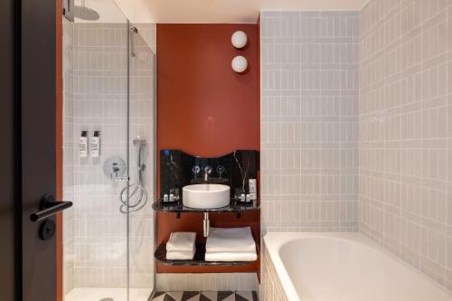 a bathroom with a tub and a sink and a shower at LE CLARK HOTEL in Paris