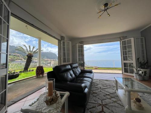 ein Wohnzimmer mit Couch und Blick aufs Meer in der Unterkunft Spring House AL in Arco da Calheta