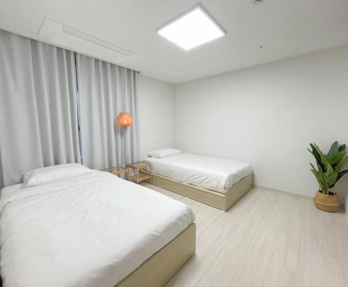 チョナンにあるAri Home - Free parking, 15mins to Cheonan Station, 20mins Sejong Emerson, 25mins to Woojeong Hillsの白いベッドルーム(ベッド2台、窓付)